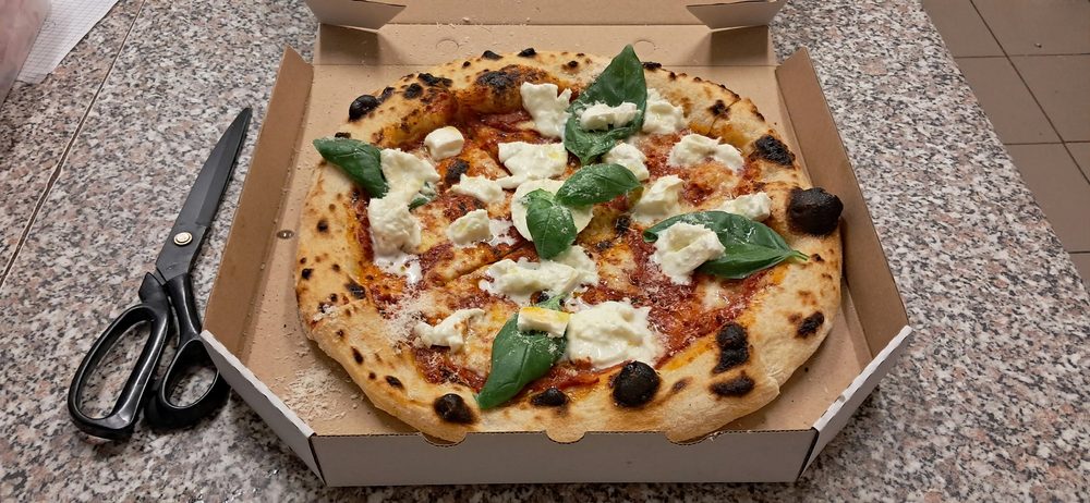 Nápolyi pizza a dobozban, magas leopárdpöttyös peremmel és bazsalikommal